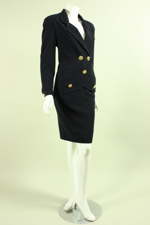 Vintage dress from Chanel dates to the 1990's and is made of dark blue lightweight wool.  From the front, it appears to be a skirt suit, but from from the back is clearly a one piece dress.  V-neck with notched lapel.  Long tapered sleeves with
