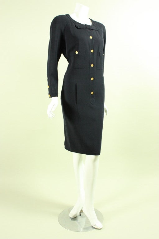 Classic Chanel dress dates to the 1990's and is made of midnight blue silk.  It is fitted throughout with gold button details.  Center front placket.  Round neckline with center front bow.  Patch pockets at side front waist.  Lined.

Labeled size