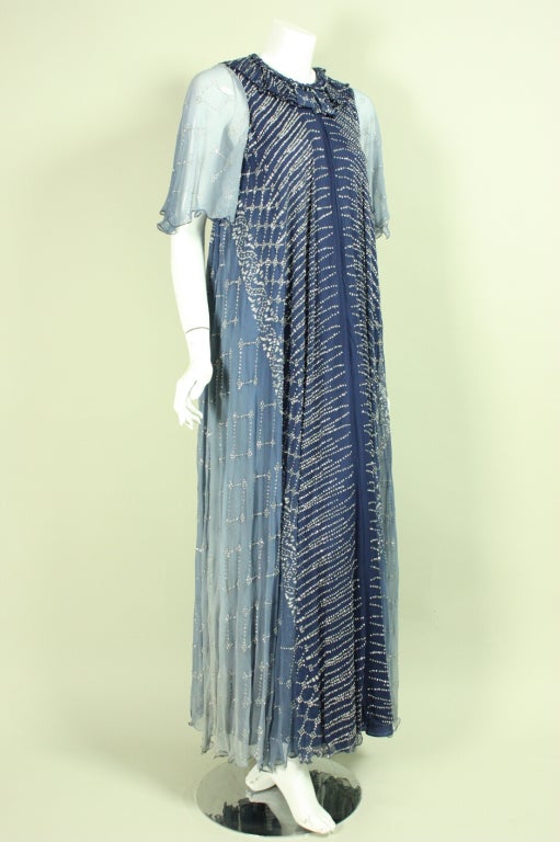 Vintage gown from Gina Frattini dates to the 1970's and is made of blue ombré silk chiffon that is covered allover with dots of silver glitter.  Round ruffled neckline.  Elbow-length sleeves.  Full length.  Lined.  Center back zipper.

Labeled a