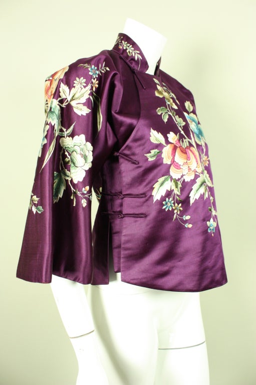 Vintage Chinese export jacket likely dates to the 1930's and is made of plum-colored silk satin.  It features allover hand-embroidered flowers in bright colors.  Stand collar.  3/4-length sleeve.  Side frog closures.  Fully lined.

There is no
