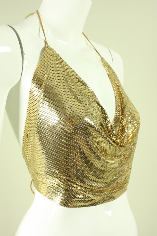 Super sexy halter top is made of gold-toned metal mesh and dates to the 1970's.  It features ties that tie around the neck and waist.  Plunging cowl neckline can be controlled by tightening or loosening the neck straps.  Unlined.

Adjustable and