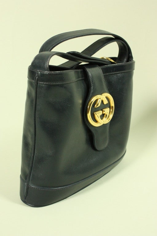 Vintage handbag from Gucci dates to the 1980's and is made of buttery soft navy leather.  It has a panel of leather that snaps the handbag closed.  Classic gold-toned interlocking G's metal logo.  Adjustable strap.  Interior side pocket with