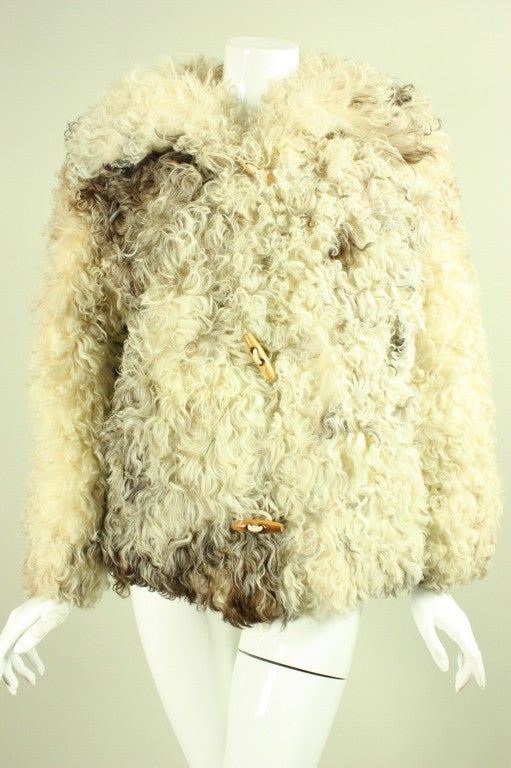 Vintage fur jacket from Revillon dates to the 1970's and retailed at Saks Fifth Avenue.  It is made of a mixture of beige and brown curly lamb.  Three center front toggle closures.  Oversized collar has brown suede on the underside.  On the