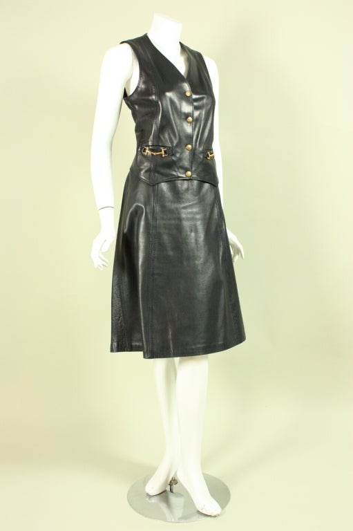 Two-piece ensemble from Celine dates to the 1970’s and is made of navy leather.  Vest has a v-neck, gold-toned hardware, and center front snap closures.  Straight skirt has zippered closure.  Both pieces ae lined.

Labeled size