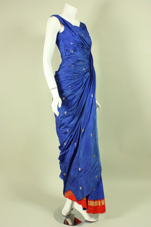Vintage evening gown dates to the 1950's and is made of a blue silk sari with a red border.  Asymmetrical neckline.  Sleeveless.  Fitted throughout.  Gathering along the left side bodice creates a focal point.  Center back zipper.  Lined in the
