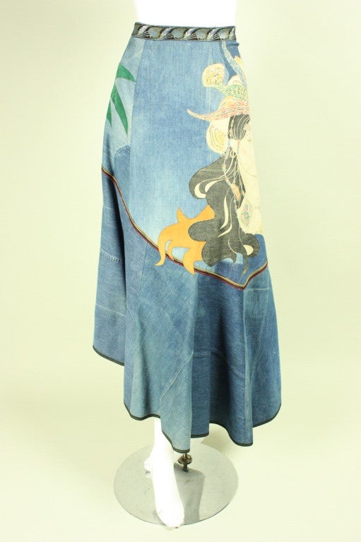 Vintage skirt from Roberto Cavalli dates to the 1970's and is made of softly faded blue denim.  It features graphic suede appliques.  Waistband is painted to look like peacock feathers.  Asymmetrical hem.  Zip closure.  Unlined.

Labeled a vintage