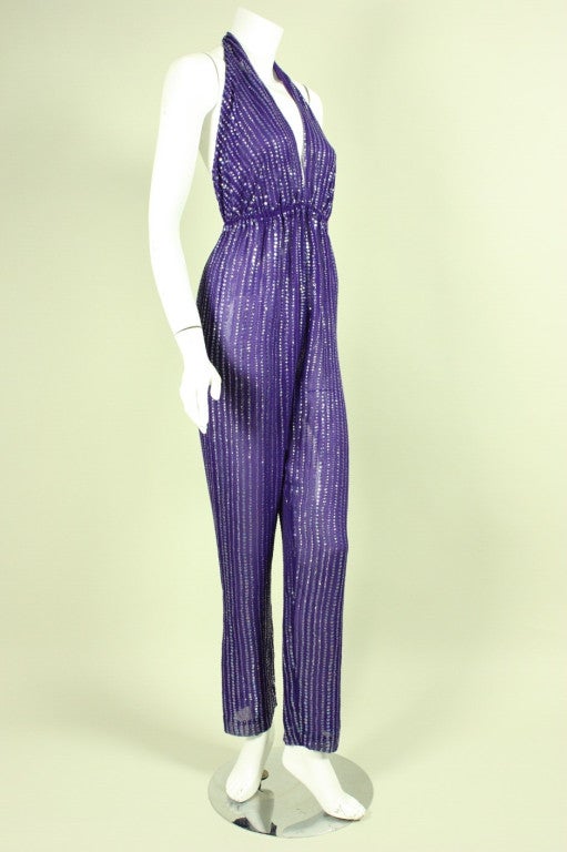 Iconic Halston ensemble dates to the 1970's and is made of purple silk chiffon that is covered in rows of hand-sewn iridescent sequins of varying sizes.   Backless jumpsuit features a halter neckline with a hook and eye closure and elasticized