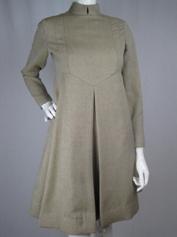 Taupe wool dress from American designer, Geoffrey Beene.  Wide a-line shape is formed from inverted pleats on the front and sides that release just below bust.  Long tapered sleeves with slits at cuffs.  Center back zip. 