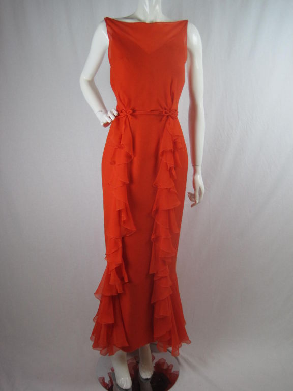 1970's tangerine orange chiffon gown with matching bolero by Helen Rose.  Dress is sleeveless, has high boat neck, and scoop back.  Two rows of ruffles cascade down the front and curve around the back below the knee to create an almost fishtail