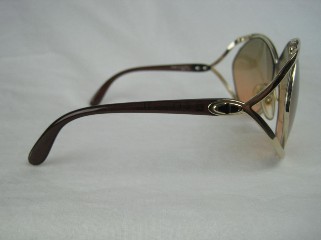 Iconic Christian Dior sunglasses with criss-cross front and open sides.  Gradient sepia-toned lenses.  Gold-toned frames.  Transparent brown arms.  CD logo at temples.  Plastic nose pieces.<br />
<br />
Measurements-<br />
<br />
Temple to