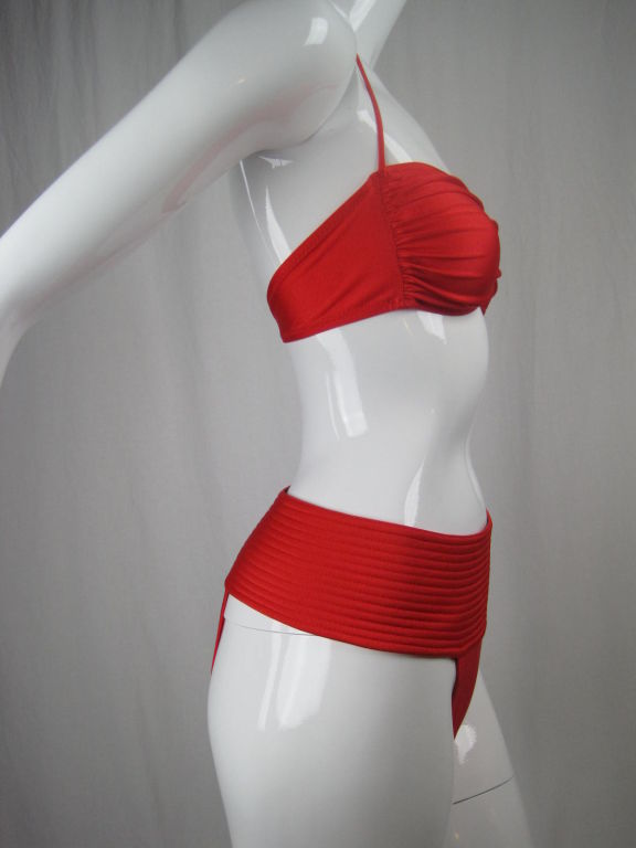 Bright red bikini by Gideon Oberson. Bandeau-style top has spaghetti straps that tie at back neck.  Bottom has a wide quilted waistband, a vertical row of hooks and eyes on left side, and Brazilian cut back.  Unlined.<br />
<br />
Labeled European