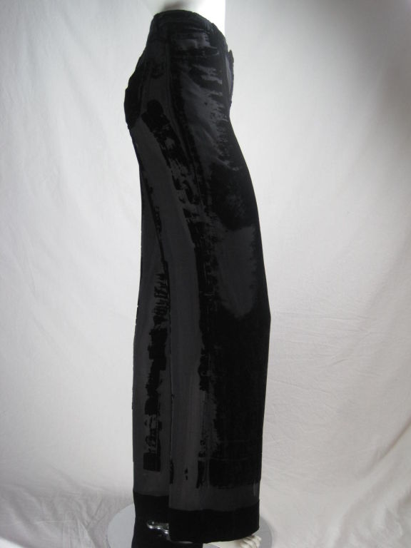 Jean Paul Gaultier trousers with jeans-like detailing.  Made of black rayon/silk velvet in an abstract burn out pattern.  Wide straight leg.  Flat front.  Lapped zip fly.  Front slant pockets.  Back patch pockets.  Top stitched seams.  Waistband