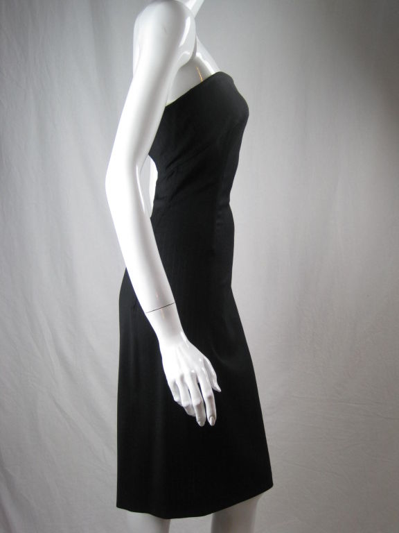 Strapless, body-conscious dress from Dolce & Gabbana. Dark charcoal gray, pinstriped wool gabardine blend.  Attached interior boned support made out of stretch white netting.  Four pieces of boning in dress.  Center back invisible zip.  Unlined.<br