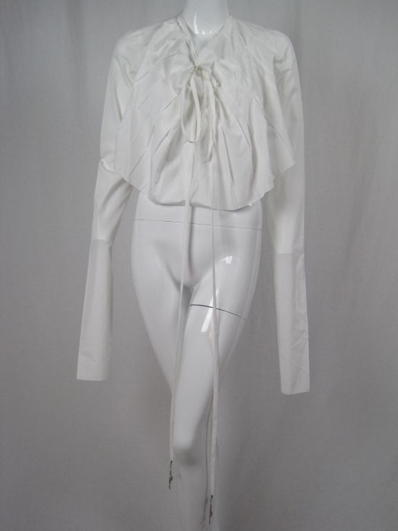 Gaultier white cotton blouse.  Extra long sleeves bunch up throughout forearm.  V-neck has long ties that gather on o-rings.  Asymmetrically pleated front.  Silver-toned metal charms hang on end of ties.  Unlined.<br />
<br />
Labeled It 38, Fr