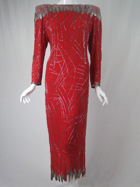 Fabrice red silk gown.  Rows of unevenly spaced silver bugle beads intersect organically at irregular intervals. Deep cowl back is entirely covered with glass seed beads.  High boat neck front.  Zigzagged hem that is 8