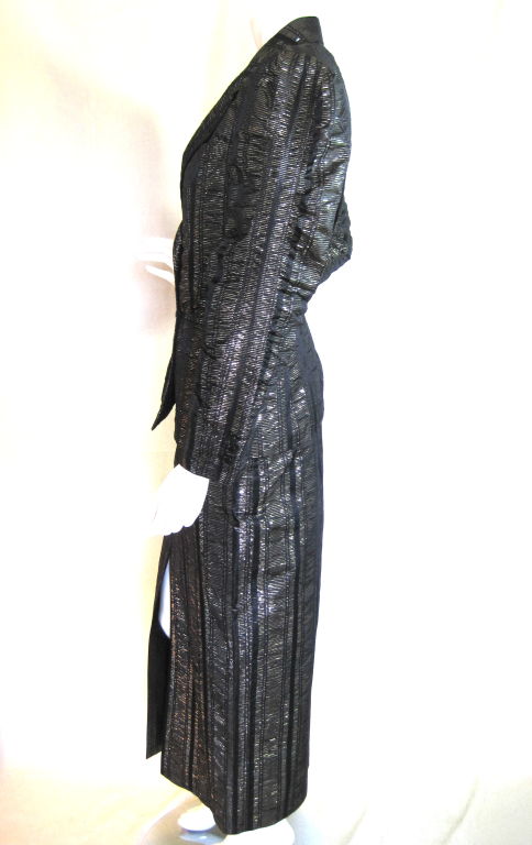 1980's skirt suit by Ted Lapidus is made out of black and gold irregularly striped lamé. The jacket has a notch lapel, ruched sleeves, is double breasted, has three button cuffs, two hip patch pockets, and one breast pocket. The straight skirt has