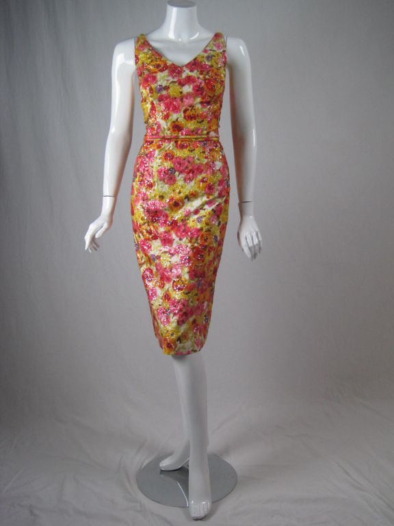 1960's cocktail dress with vivid floral print.  Brightly colored cotton sateen is nearly covered with hand-sewn sequins.  Fitted throughout.  Sleeveless.  V-neck front and back.  Center back zip.  Lined.  Self belt.<br />
<br />
No size label.<br