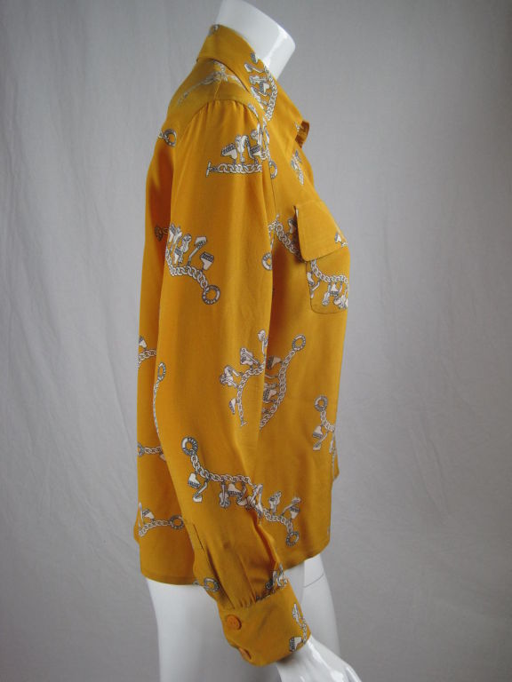 Mustard yellow silk with chain link and charm print.  Double front breast patch pockets with flap closure.  Button front.  Long sleeves with button cuff.  Unlined.<br />
<br />
Labeled size 38.<br />
<br />
Measurements-<br />
<br />
Bust: