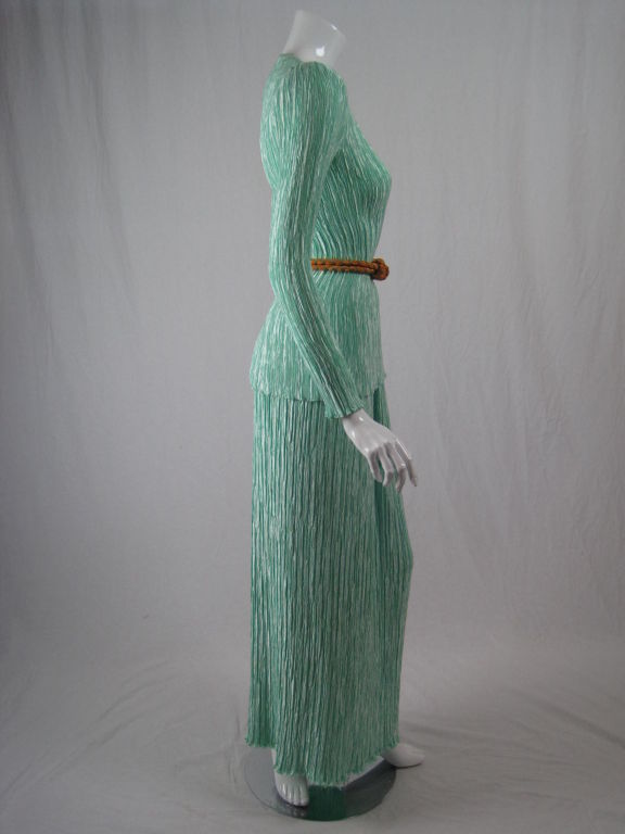 Mint green pleated ensemble in the style of Fortuny.  Blouse has squared scoop neck, no closures, and small shoulder pads.  Ankle-length skirt has side zip.  Marigold belt is trimmed with thick metallic gold threads.<br />
<br />
Measurements<br