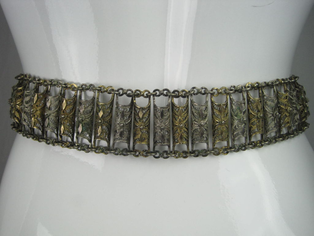 Marked down from $695.

Antique wedding belt from the Balkans circa late 19th century to early 20th century. Exquisite filigree detail.  Alternating silver and gold-plated pieces.  Large buckle with pendants.  

Almost identical piece housed in