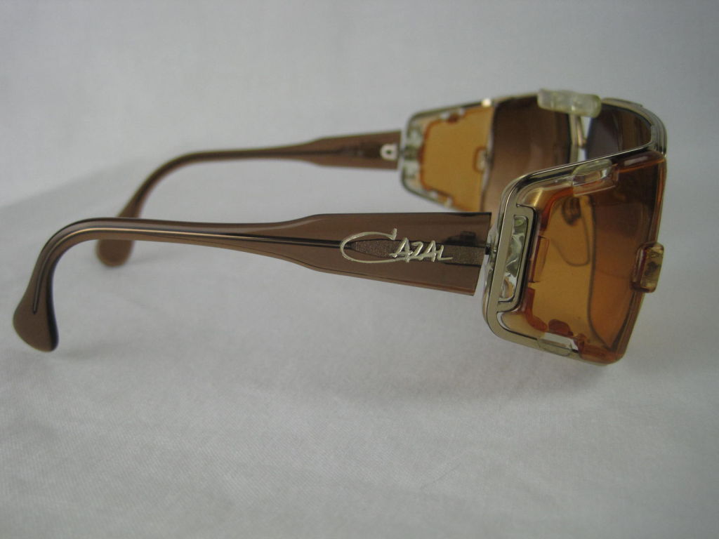 Vintage Cazal sunglasses with transparent orange side inserts.  Gold-toned frames with brown fleck.  Squared aviator shape.  Gradient lenses.  
