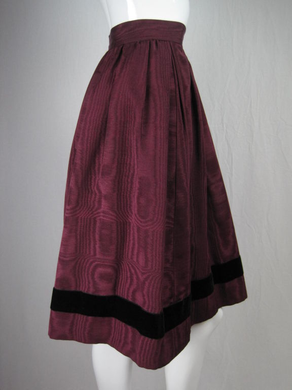 1970's Yves Saint Laurent skirt.  Plum-colored moiré with black velvet trim at hem.  Pleated.  Back zip with hook and eye closure at waist.  Side pockets.  Fully lined.

Labeled size 36.

Measurements-

Waist: 24