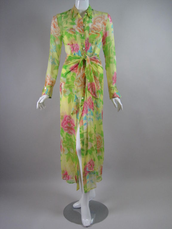 Sheer shirtdress from Kenzo.  Bright yellow silk chiffon with vibrant multicolor floral print.  Attached over-skirt is stitched to dress at center back and ties in the front to look like a sarong.  Long sleeves with single button cuffs.  Two front