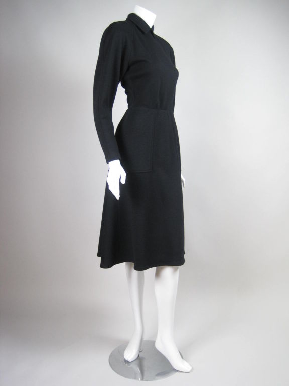 Classic black wool knit dress from Bernard Perris and Amen Wardy.  Round neck with turn down point collar.  Bias-cut skirt has body, especially in the back.  Raglan sleeves.  Zippered cuffs.  Center back zip.  Unlined.

Description: Labeled size