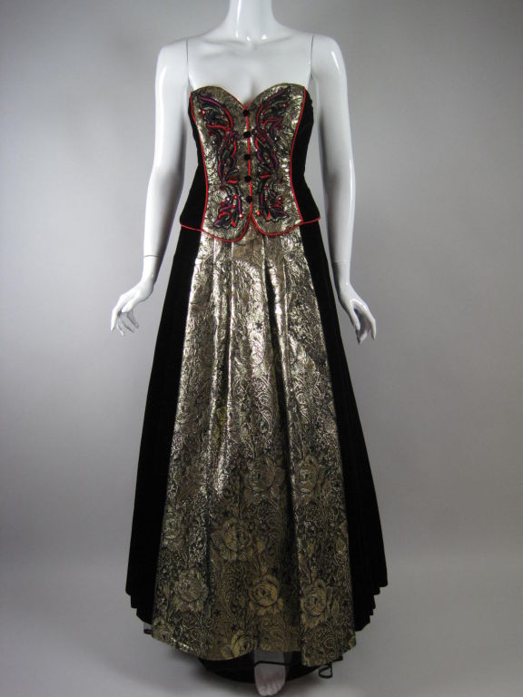 Two-piece evening ensemble from Escada.  Strapless gown has gold brocade center panel with rhinestones and embroidery, is fully lined including tulle underskirt, and has center back zipper.  Bolero has no closures, is lined with bright red fabric,
