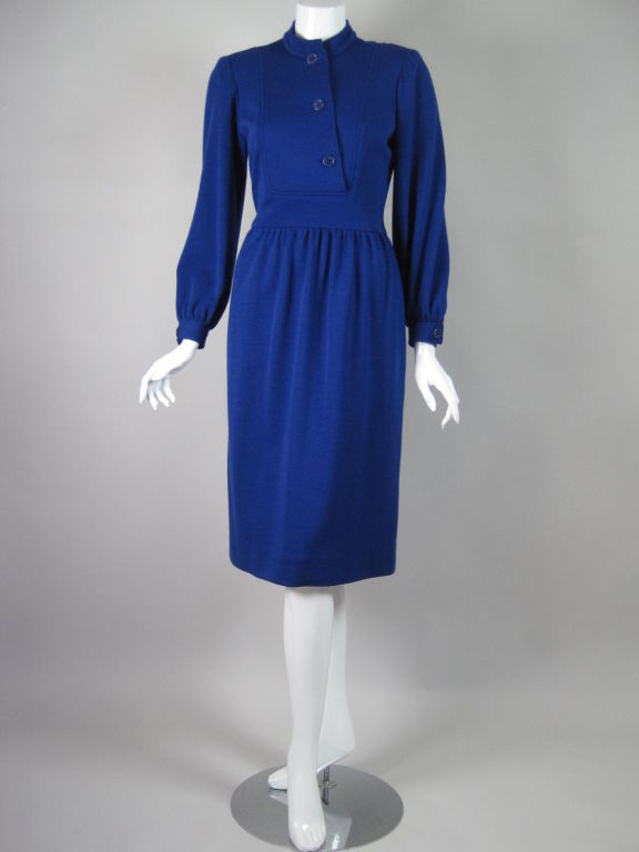 1980's Albert Nipon royal blue knit dress.  Mock neck with diagonally buttoned placket.  Long sleeves have button cuff.  Straight skirt is gathered at waistband.  Hip pockets.  Lightly padded shoulders.  Side zip.  Unined.<br />
<br />
No size