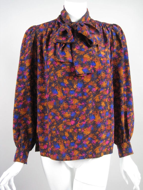 1970's blouse from Yves Saint Laurent.  Rust, blue, magenta, and marigold splotch printed silk.  Center front button closure at neckline creates keyhole opening.  Wide neck tie.  Buttoned cuff.  Boxy fit.  Unlined.

Labeled size
