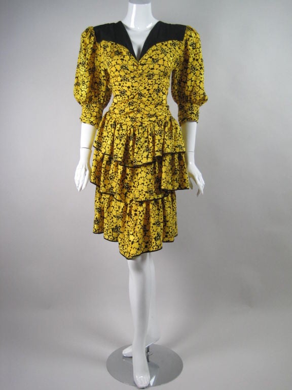 Brightly-colored party dress from Jean-Louis Scherrer.  Yellow silk ground with allover floral print in black.  Short bubble sleeves with button cuffs.  V-neck.  Triple tiered ruffle skirt.  Shirred bodice.  Zip back.

No size