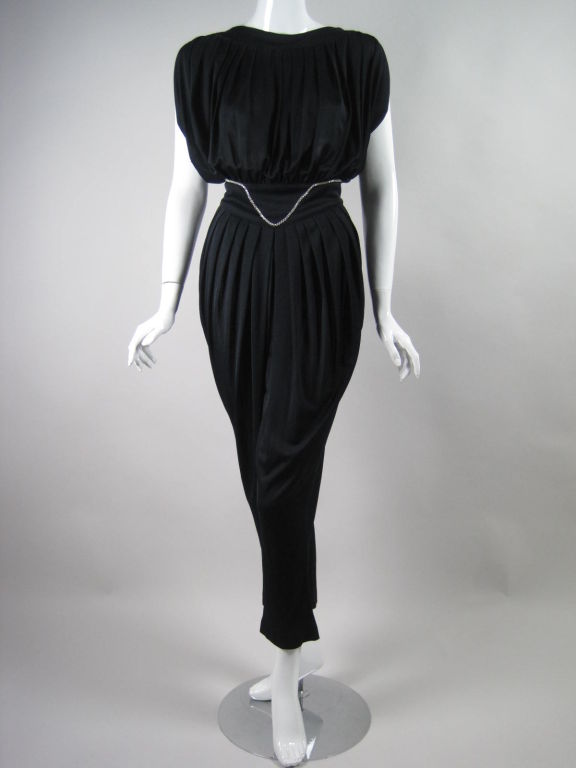 Radley jumpsuit dating to the 1970's.  Lightweight black jersey with a rhinestone accented waistband.  Bodice has a slight boat neckline, draped cap sleeves, and is pleated at neckline and gathered at waist.  Tapered leg.  Three button closure at
