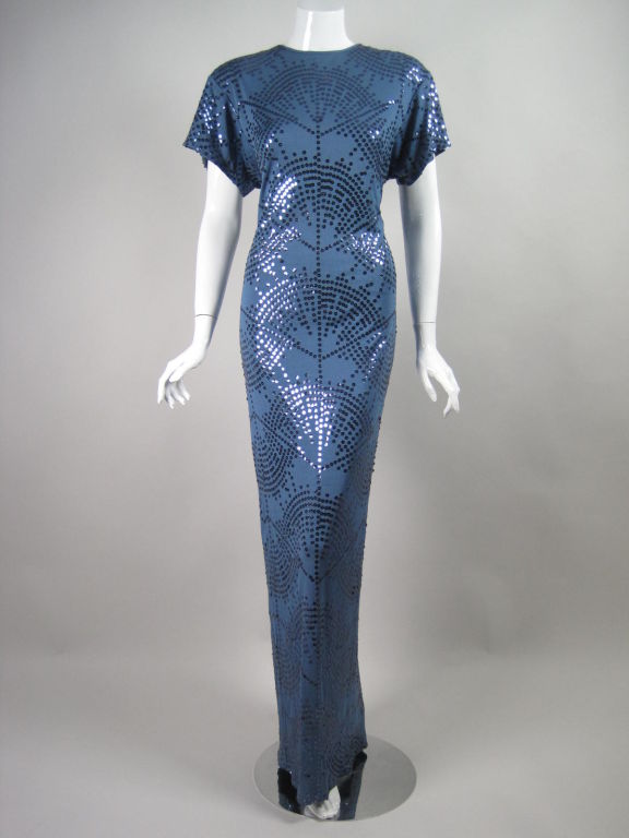 Early 1980's evening gown from Giorgio Beverly Hills.  Slate blue jersey is adorned with sequins arranged in a radiating fan pattern.  Round neck.  Short sleeves.  Keyhole opening at back neck with single hook and eye closure.  Center back slit. 