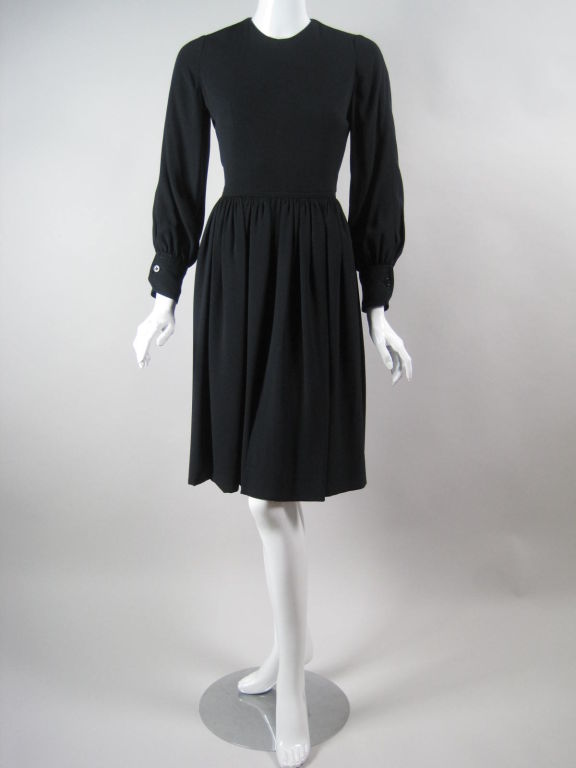 James Galanos for Amelia Gray dress circa 1970's.  Fully lined black jersey.  Round neck.  Long sleeves with button cuffs and snap closures.  Skirt has gathers at waist and center front and back vents.  Center back zip.  Fully lined.

No size