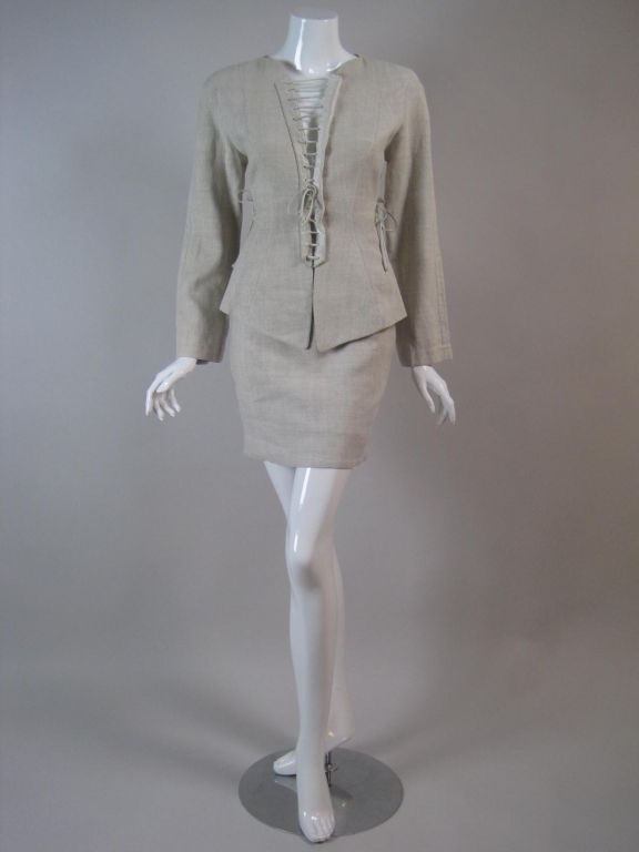 1980's suit from Thierry Mugler.  Natural-colored linen with corset-like lacing in the front and sides of the jacket.  Fitted jacket is cleverly fastened with snaps underneath one side of the lacing.  Fitted miniskirt has center back zipper.  Both