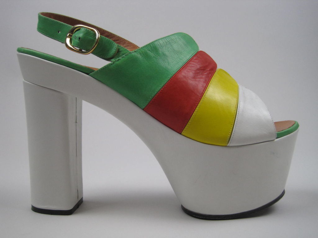 1970's platform heels from Enzo of Roma.  Stark white leather base is topped by brightly colored strips of red, yellow, and green leather.  Adjustable back strap is fastened by gold-toned buckle.  Open toe.  Leather interior.  Rubberized sole. 