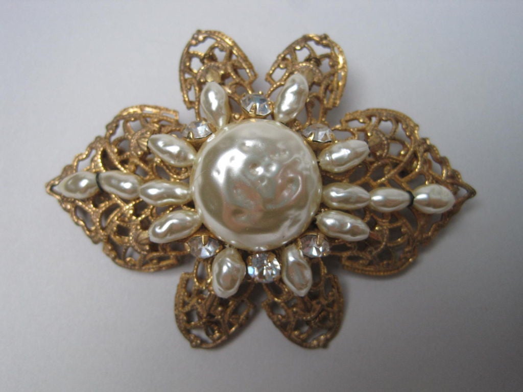 Lovely signed piece from Miriam Haskell.  Faux pearls and rhinestones set in gold-toned filigree.  Shaped like a flower.

Measurements-

Length: 2 3/8