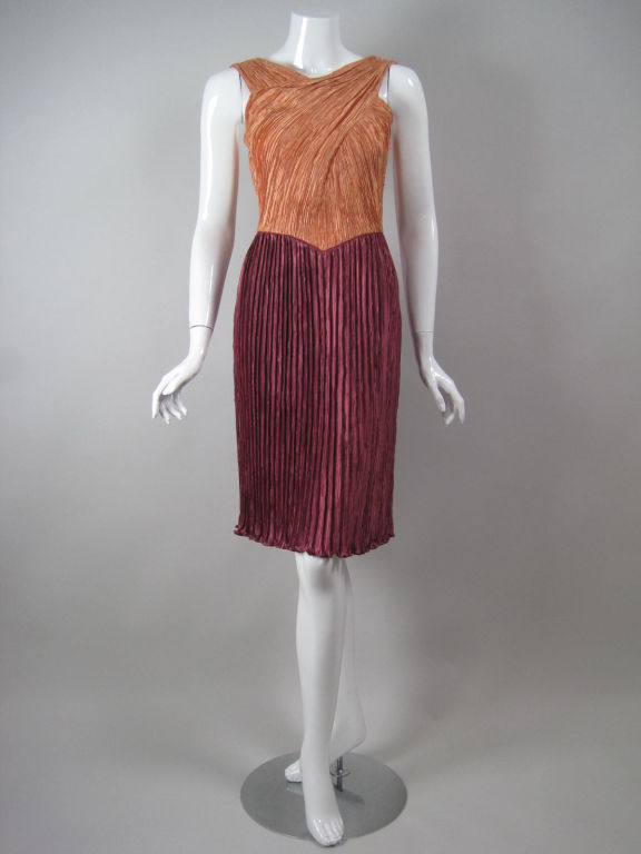 Mary McFadden Couture cocktail dress is made out of her fully pleated signature fabric.  Peach-colored, sleeveless bodice has crisscrossed detail and high v-neck.  Wine-colored straight skirt.  Center back zipper.

No size