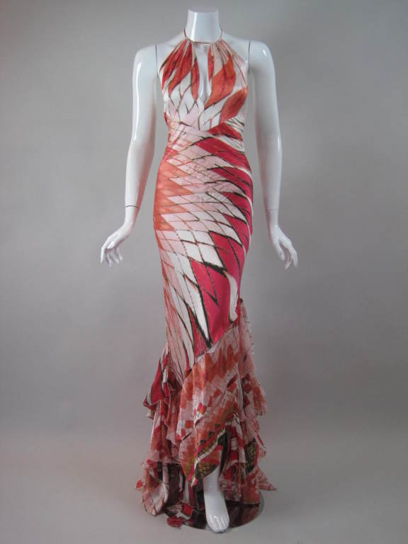Contemporary bias-cut gown from Roberto Cavalli is made of white silk charmeuse with a geometric snakeskin print in magenta, coral, and pale pink.  Ruffled, fishtail hem forms a slight train.  Halter bodice has keyhole neckline and center back tie. 