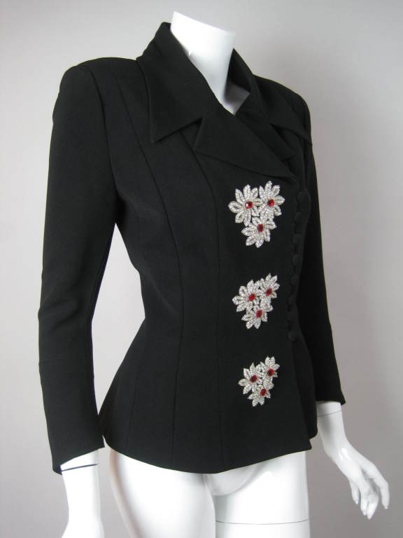 Fitted jacket from Karl Lagerfeld with exquisite beadwork.  Three groups of three flowers each are made out of sequins, beading, embroidery, and large ruby red rhinestones.  Large collar with notch lapel.  Covered button closures.  Fully lined.  <br