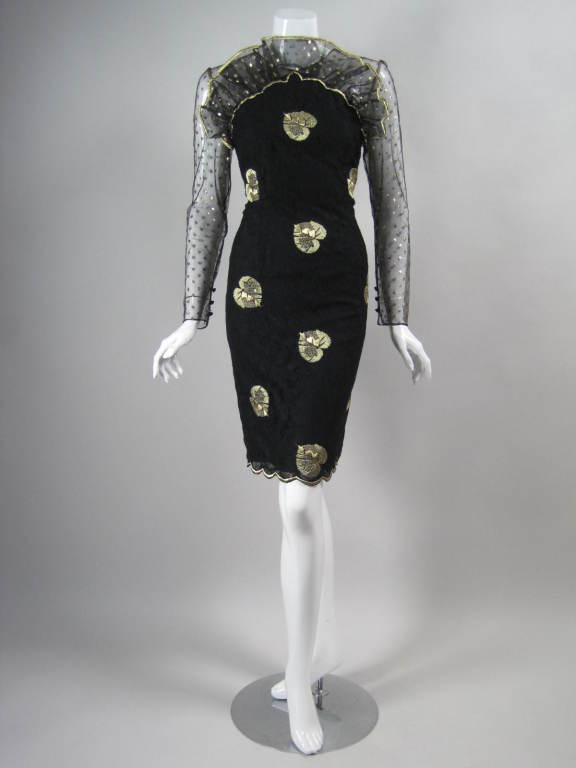 Fun cocktail dress from Bill Blass is made out of black floral lace that is over-embroidered with large gold leaves.  Upper bodice and sleeves are made out of black netting with embroidered gold dots.  Tulle "fan" extends up from