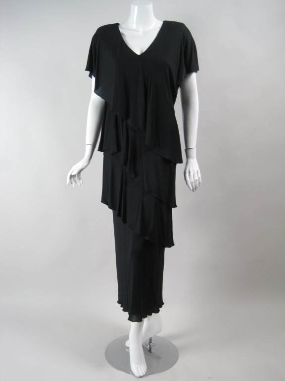 Romantic dress from iconic California designer Holly's Harp circa mid-1970's through the early 1980's.  It is made out of black matte jersey with three rows that diagonally cut across the body.  V-neck.  Short sleeves.  Heavily padded shoulders. 