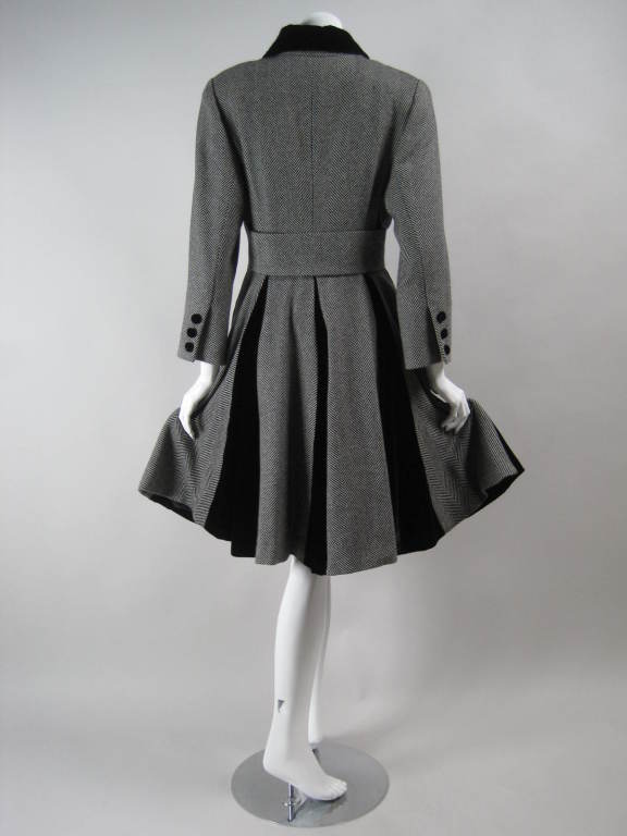 1980's Christian Dior coat has a very 1950's feel.  Black and white wool houndstooth with black velvet godets in the back skirt.  Turn-down velvet collar.  Fitted sleeves have three decorative velvet-covered buttons at cuffs.  Fully lined.

No