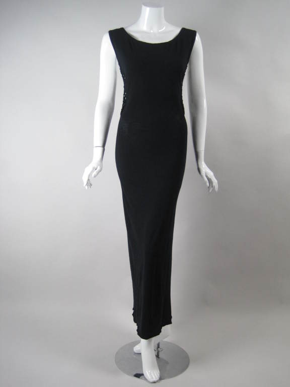 Daring tank gown from Jean Paul Gaultier is made out of black stretch cotton and features a dramatic open back. Bands of torn fabric drape across the back and are tied to the dress at the side seam.  Sleeveless.  Scoop neck.  No closures.