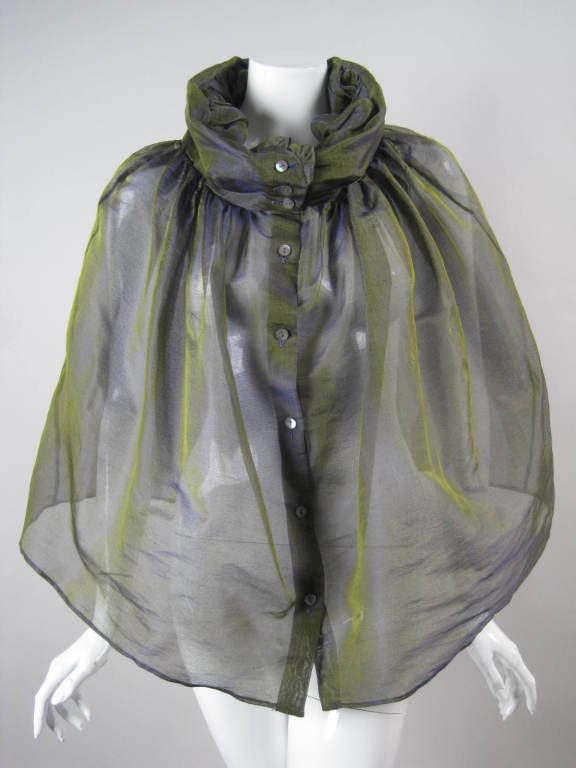 Ethereal sheer capelet is made out of blue and green silk sharkskin.  Center front button closure.  Collar can be worn tucked in or left out.  It is shown tucked in in the first six photos.  No armholes.  Unlined. 

No size.

Center Back Length: