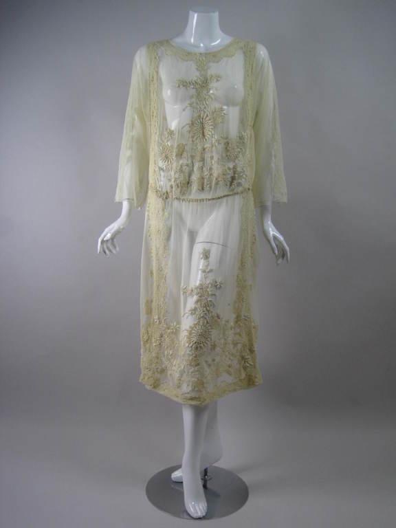 Breathtaking 1920's dress is made of soft ecru netting with raised floral hand-embroidery that is done in satin stitches and French knots.  Scalloped Irish crochet inserts.  Long sleeves have band of embroidery running down the arm and wide cuffs