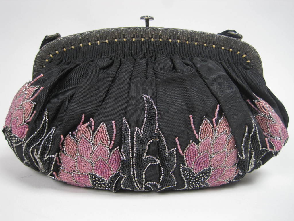 1920's evening handbag is made out of black silk faille with exquisite floral beadwork that appears to be "growing" from the bottom of the bag.  Flowers are made up of three different shades of pink and trimmed with silver metal beads. 