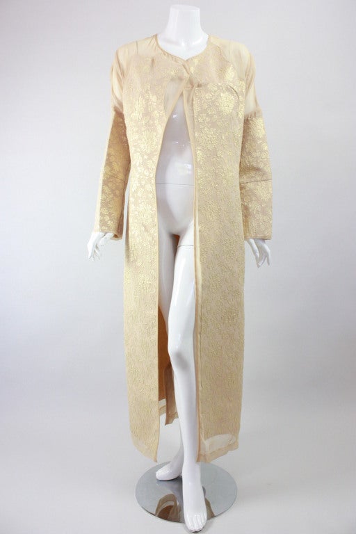 From her Fall/Winter 1997 Ready-to-Wear collection, comes this deconstructed coat from fashion genius Rei Kawakubo.  It is made out of beige and gold floral brocade lamé with has kimono-like styling.  Gold brocade is appliqued onto netting in an