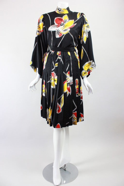 Three piece outfit from Michael Novarese circa 1980s, is made of black silk with a windowpane weave, printed with a bold floral pattern in white, red, and yellow.  Blouse has a mock neck, 7/8 length wide sleeves, padded shoulders and center back